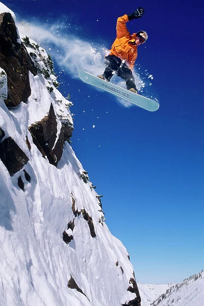 Man on a snowboard jumping off a cornice at Snowbird Resort in Little Cottonwood