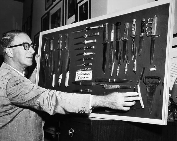 CAREY ESTES KEFAUVER (1903-1963). American Democratic politician, who introduced a bill to prohibit interstate trafficking of switchblade knives, posing with a display of confiscated switchblades, 17 July 1957