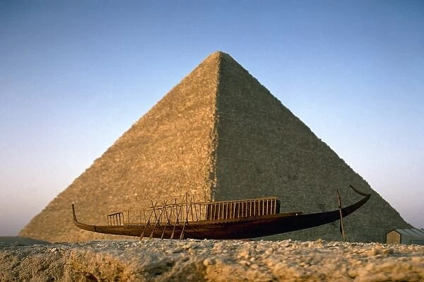 EGYPT: CHEOPS PYRAMID. A view of the Great Pyramid of Cheops in Giza, Egypt, with a model funerary boat in the foreground. Photographed c1970