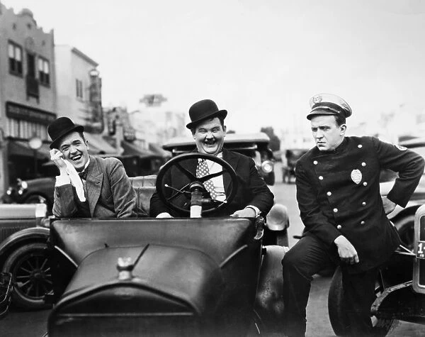 LAUREL AND HARDY, 1928. Stan Laurel, left, and Oliver Hardy with a police officer in the silent film Leave Them Laughing, 1928