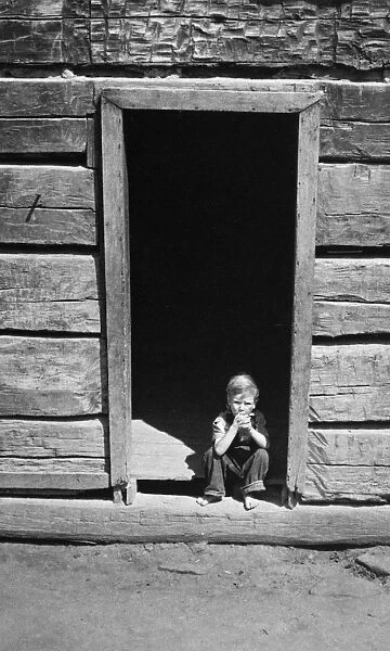 LOG CABIN, 1940. Child in doorway of an old mountain cabin made of hand-hewn logs