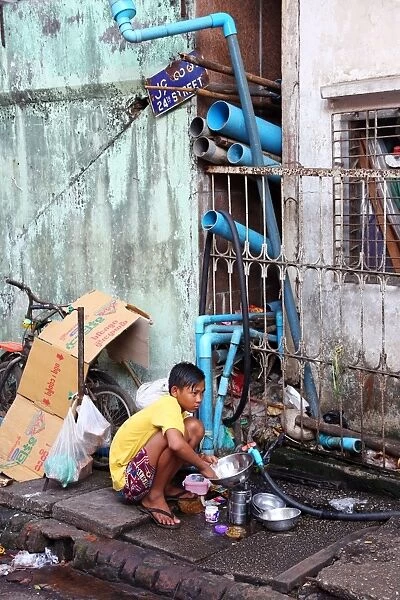 Boy washing dishes in the street, Yangon, Myanmar