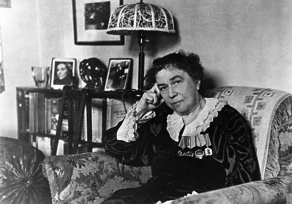 Ambassador alexandra kollontai at her home in moscow, on the bookshelf behind her is a portrait of the minister of republican spain, isabel de palencia, the author of her biography, april 1946