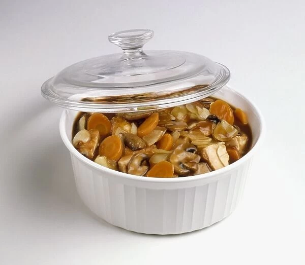 Beef casserole in white microwave dish with glass lid