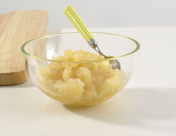 Bowl of apple puree with spoon, close-up