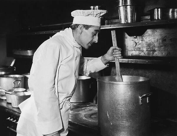 Chef stirring soup in large pot on stove