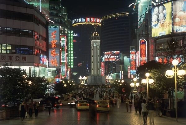China, Chongqing, Jiefangbei or Victory Monument, floodlit clock-tower surrounded by a busy shopping district