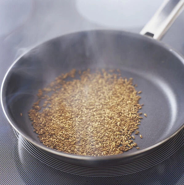 Fennel seeds dry-roasting in a frying pan