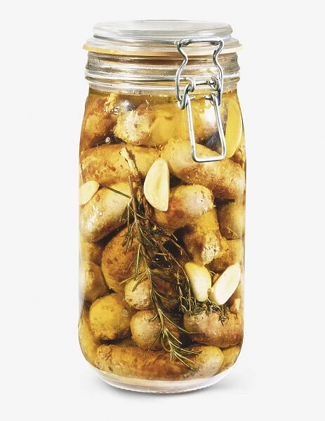 Glass jar containing sliced toulouse sausages, garlic and rosemary