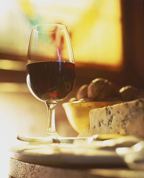 Glass of red wine with cheese and a bowl of nuts, close up, front view