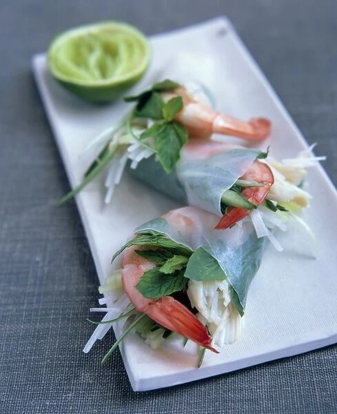 Goi Cuon, Vietnamese rice paper wrappers stuffed with prawns, vermicelli noodles, ginger and mint, on rectangular plate, lime in the background
