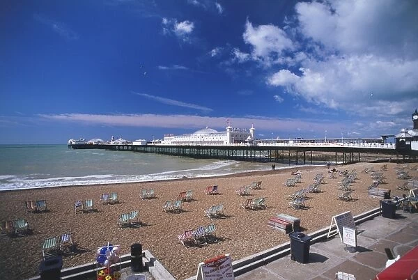 Great Britain, England, Brighton, view across sandy beach dotted with deckchairs towards Brighton Pier