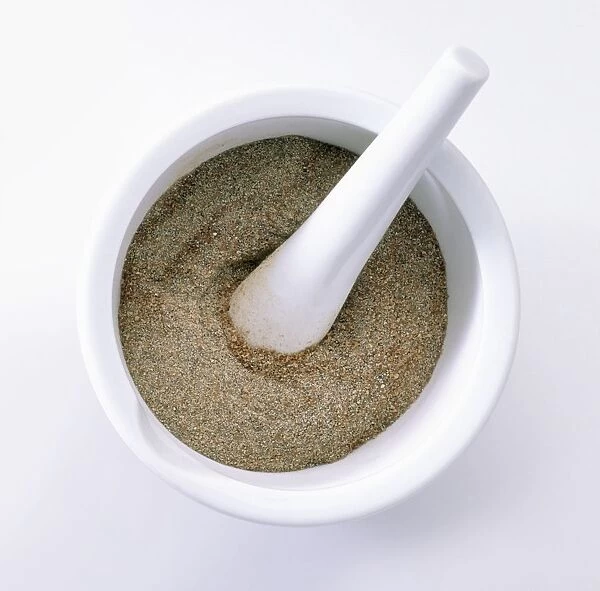 Ground cardamom with pestle in mortar, close-up, view from above