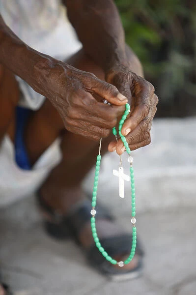 Haitian woman praying with prayer beads