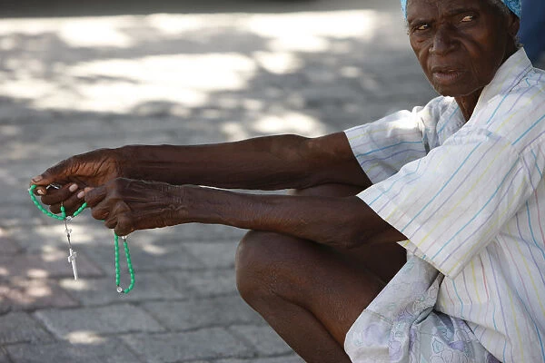 Haitian woman praying with prayer beads