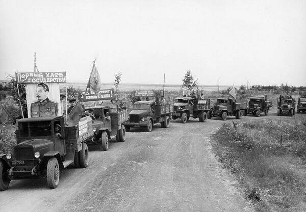 Harvest time on a collective farm in the ussr, august 1947, trucks from the stalin collective farm in the stavropol territory taking grain to the state elevator, the banner reads first bread goes to the state