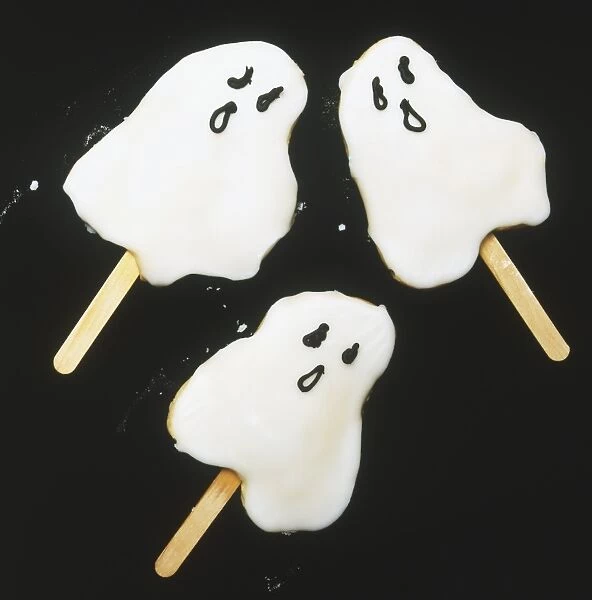 Three iced ghost biscuits on a stick