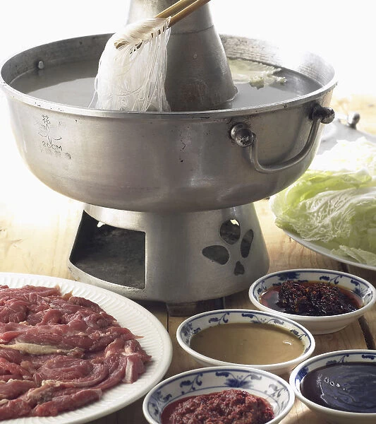 Mongolian hotpot, thinly sliced lamb, vegetables, and noodles in boiling water, served with array of sauces