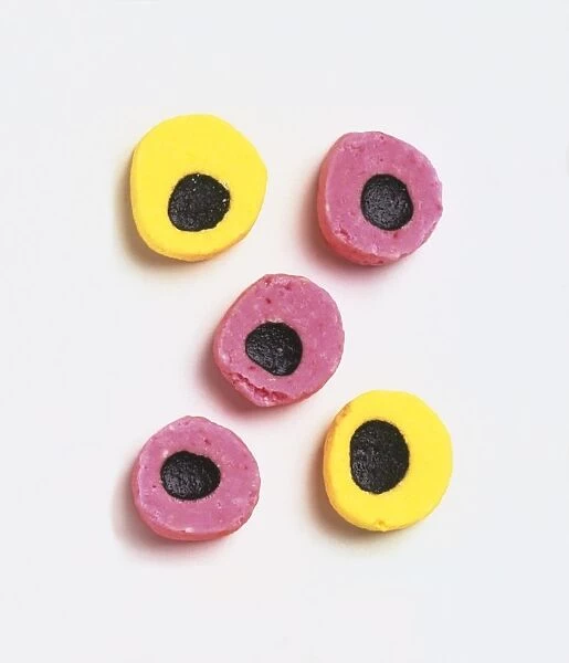Five pink and yellow sweets with liqourice in their centres