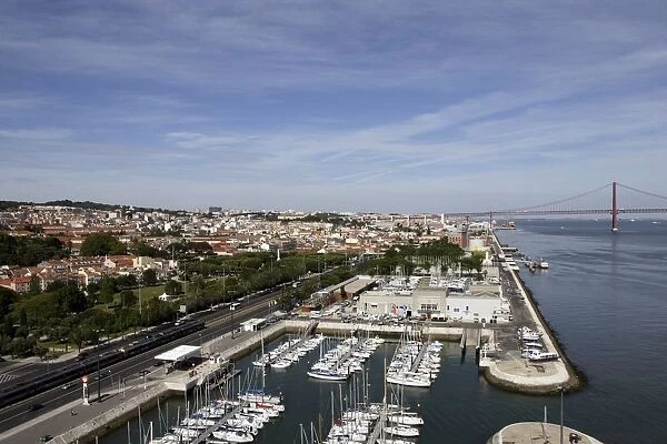 Portugal, Lisbon, view of the River Tagus and riverbank, with marina, railway line and Ponte 25 de Abril (25th of April Bridge) in the background