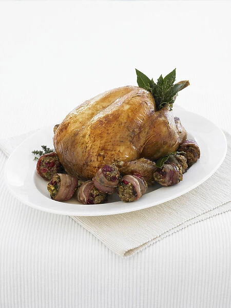 Roast turkey, served with bacon rashers stuffed with cranberries and pistachios, with a garnish of fresh herbs, close-up