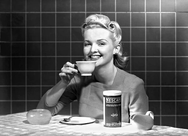 A single woman at a kitchen table enjoys a cup of Nescafe