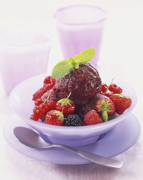 Summer fruit sorbet decorated with sprigs of fresh mint and served with fresh berry fruits including strawberries and raspberries