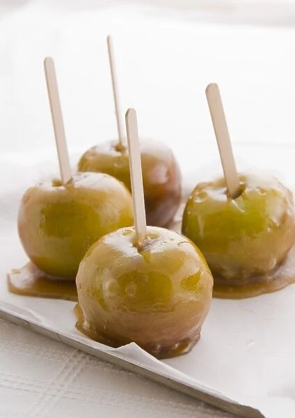 Four toffee apples on non-stick parchment paper