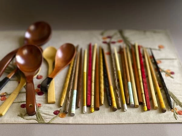 Various different chopsticks and wooden spoons laid out on place mat
