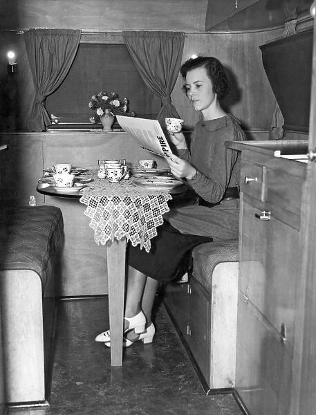 A young woman having breakfast and coffee at a table in a trailer