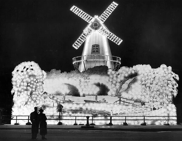 Well Lit. Visitors admiring the windmill, one of the illuminations at Blackpool