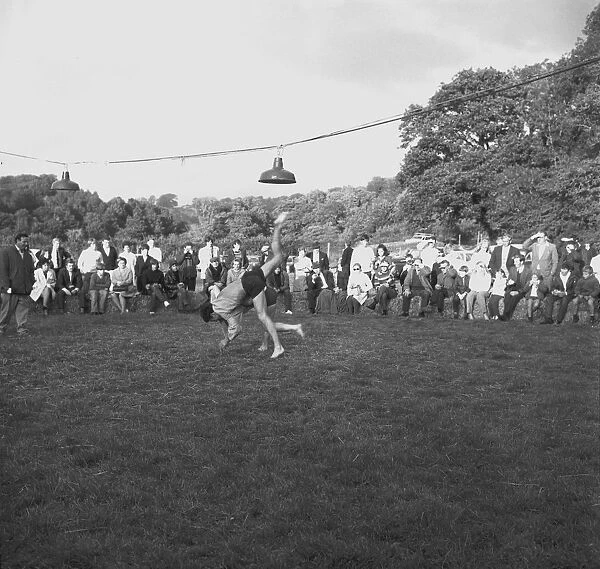 A crowd of people gathered to watch a Cornish wrestling match at an unknown location, Cornwall. 1970