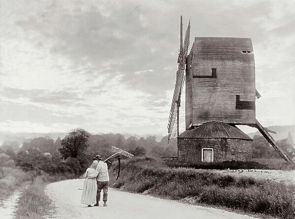 A couple of peasants arm in arm moving down a country path. A windmill can be seen on the right