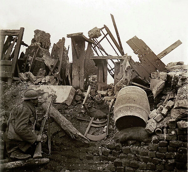 On the fighting front, a hairy man stands on the lookout, gun in hand, in the ruins of a house, 1914-1918 (b / w photo)