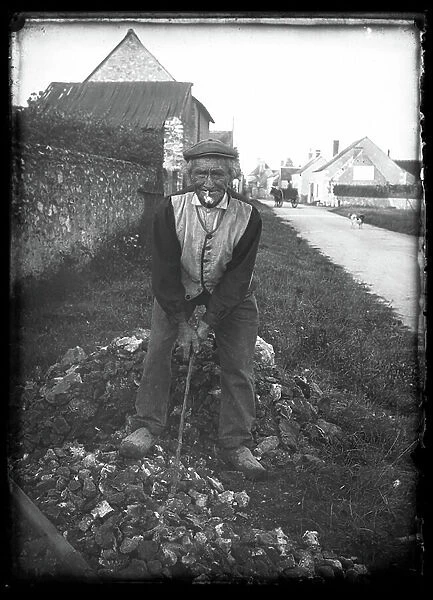 France, Centre, Indre-et-Loire (37), Ballan-Mire (ballan mire): an old man sitting on a pile of rocks with his pipe and his cane, 1920