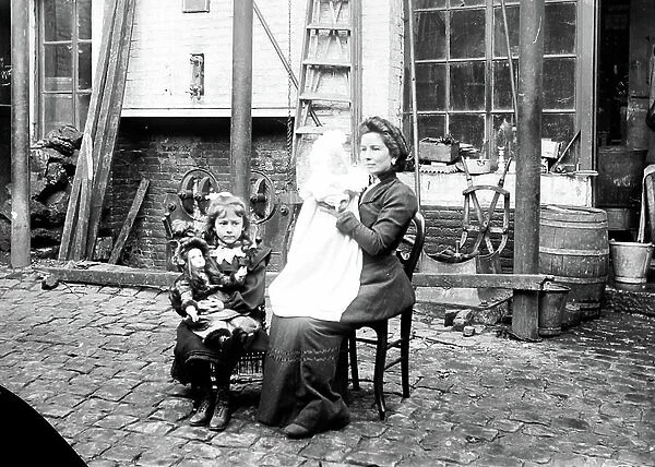 France, Centre, Loiret (45), Orleans: forging workshop with outside a woman and her baby and a little girl and her doll, 1900