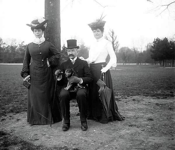 France, Ile-de-France, Paris (75): A man sitting poses around two women at the Bois de Boulogne, 1910