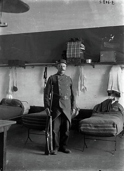 France, Ile-de-France, Paris (75): portrait of a soldier of the 2nd regiment in uniform at the barracks, at the guard at you in front of his bed, 1900