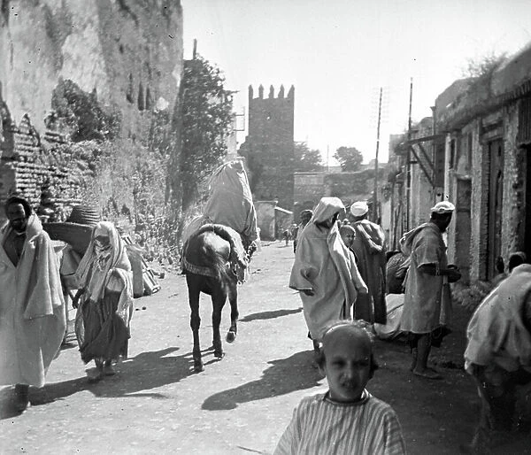 Morocco, Gharb-Chrarda-Beni Hssen, Mechra Bel Ksiri: A woman on a donkey in the middle of a village, 1910