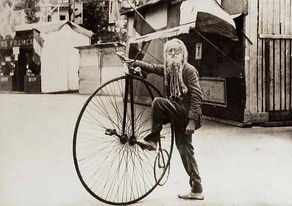 Portrait of an elderly man with a rather long and odd looking beard, standing with his bicycle