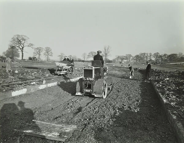 Road construction work at Chingford Estate, workers operate machinery, London
