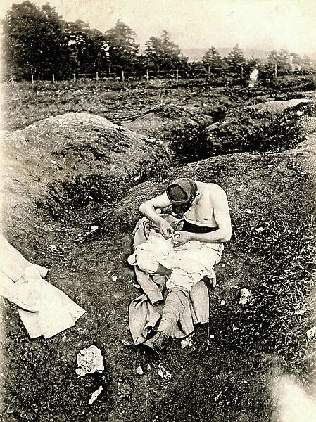 War 1914-1918: poilu seeks his lice sitting in a trench (photo)