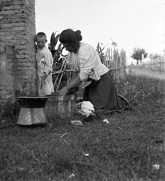Woman washing clothes while a child observes