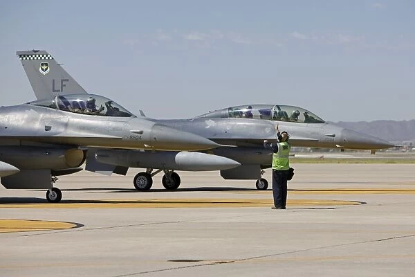 F-16 pilots work with crew chiefs on preflight checks at Luke Air Force Base