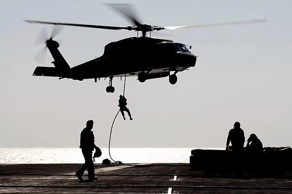 Personnel fast-rope out of an SH-60F Seahawk helicopter