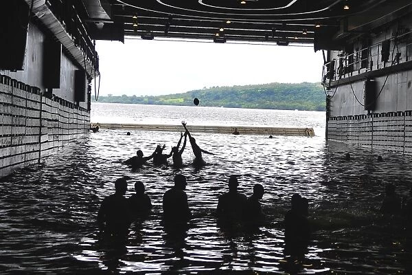 Sailors play football during a swim call in the well deck of USS Cleveland