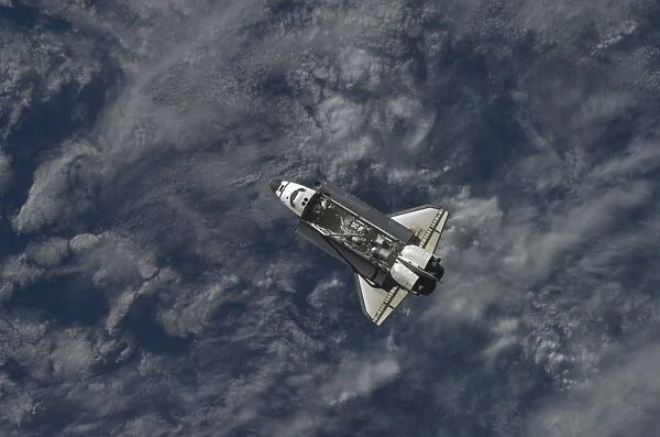 Space Shuttle Atlantis backdropped by a blue and white part of Earth