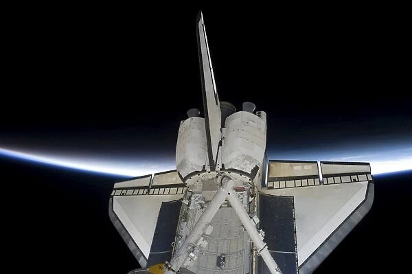 Space Shuttle Discovery intersecting the thin line of Earths atmosphere, while docked