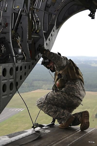 U. S. Army crew chief checks a landing zone from the ramp of an MH-47G Chinook
