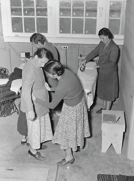 Camper receives help in fitting a coat from WPA sewing instructor, FSA, California, 1938. Creator: Dorothea Lange